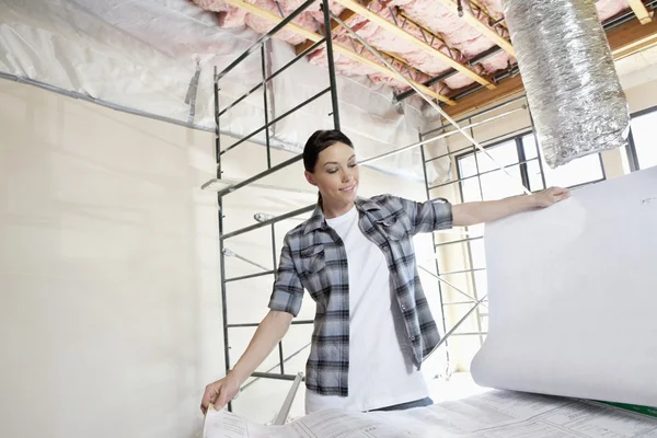 Belo empreiteiro adulto médio olhando para os planos de construção no canteiro de obras — Fotografia de Stock