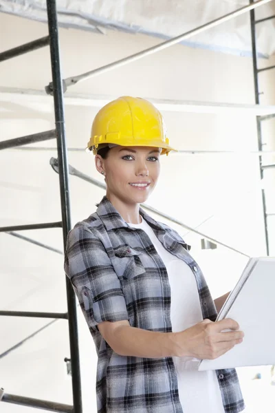 Portret van mooie midden volwassen architect dragen van veiligheidshelm met blauwdrukken — Stockfoto