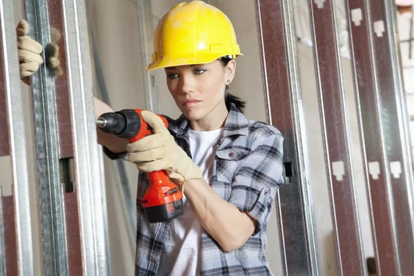 Mitten av vuxen kvinnlig entreprenör borrning på byggarbetsplats — Stockfoto