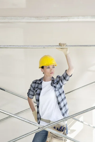 Framifrån av mitten av vuxna arbetstagare tittar bort stående under byggnadsställning — Stockfoto