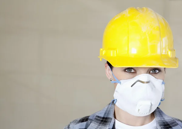Portret van vrouwelijke werknemer stofmasker en veiligheidshelm dragen over gekleurde achtergrond — Stockfoto