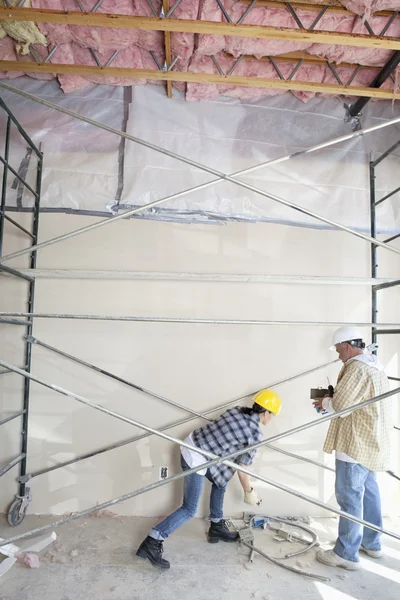 Male and female worker standing under scaffold at construction site — Stock Photo, Image