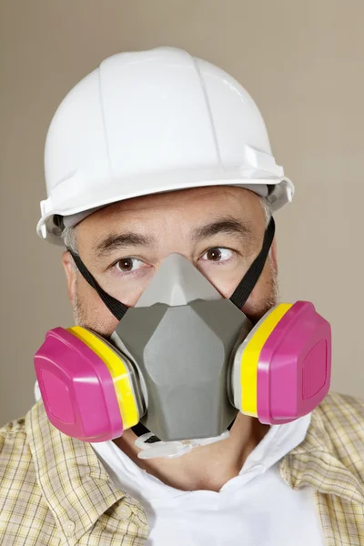 Close-up portrait of contractor with dust mask over colored background — Stock Photo, Image