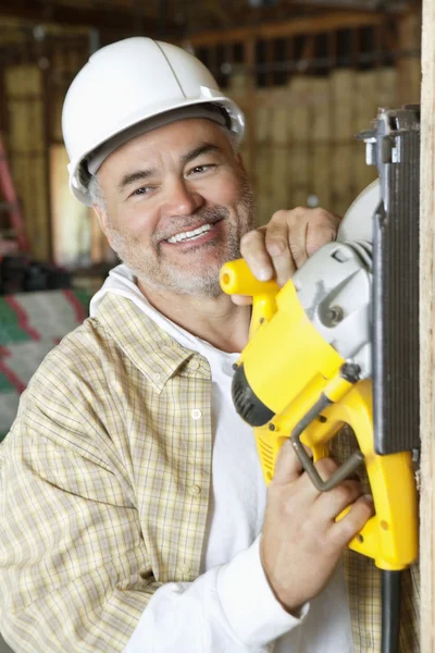 Feliz trabajador de la construcción macho maduro cortando madera con una sierra circular — Foto de Stock