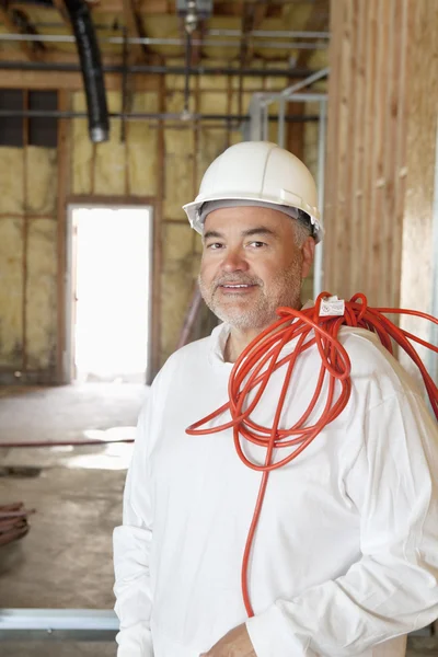 Retrato de un trabajador de la construcción con un cable eléctrico rojo —  Fotos de Stock