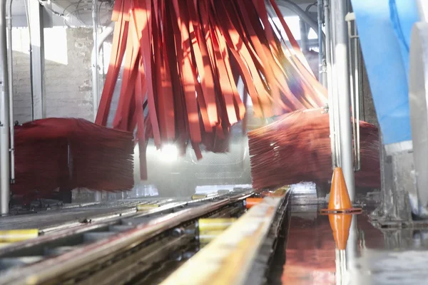 Vehicle moving on conveyor going through cleaning in car wash — Stock Photo, Image