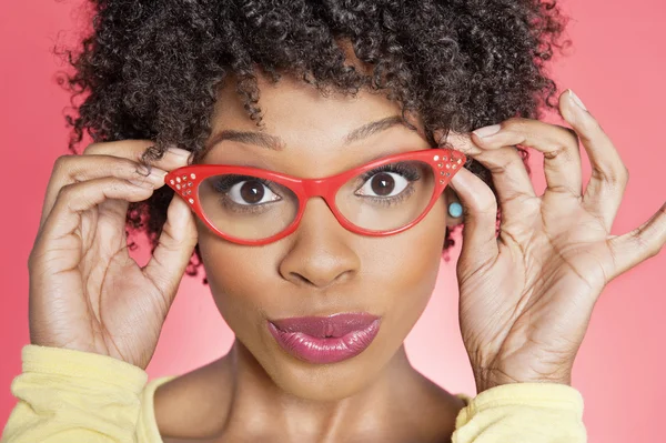 Retrato de uma mulher afro-americana vestindo óculos de estilo retro sobre fundo colorido — Fotografia de Stock