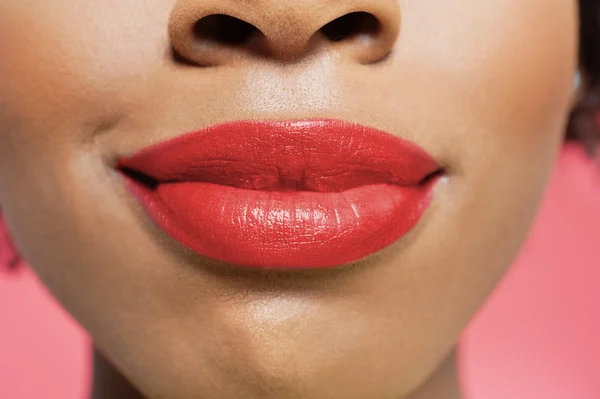 Vista de cerca de los labios rojos de una mujer afroamericana sobre un fondo de color —  Fotos de Stock