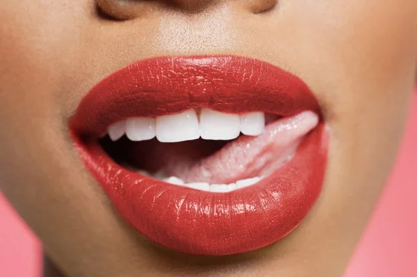 Imagen recortada de la mujer lamiendo lápiz labial rojo — Foto de Stock