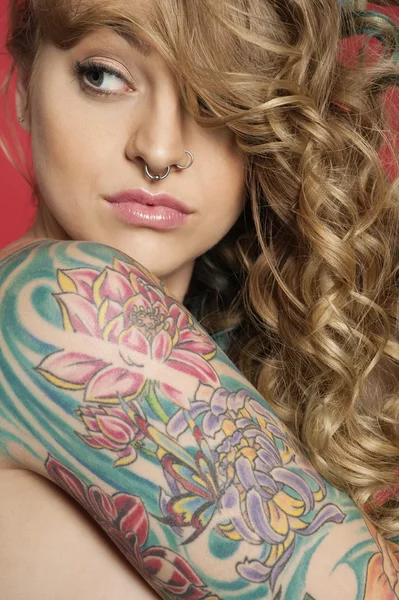 Красивая молодая женщина смотрит сбоку с татуированной рукой — стоковое фото