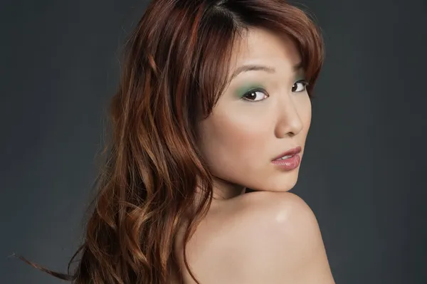 Mulher chinesa jovem bonita olhando para trás sobre fundo colorido — Fotografia de Stock