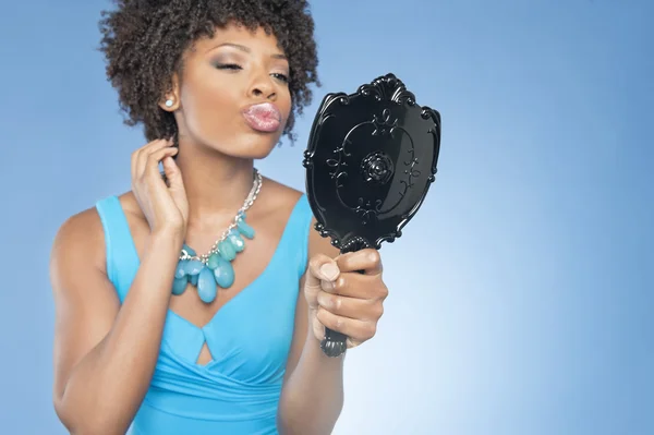 Atractiva mujer afroamericana puckering mientras se mira en el espejo sobre fondo de color — Foto de Stock