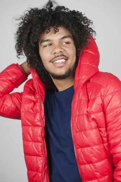 Счастливый молодой человек в куртке в капюшоне, отводя взгляд от цветного фона — стоковое фото