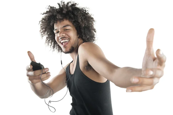 Portrait of a happy young man in vest dancing to tunes of mp3 player over white background — Stock Photo, Image