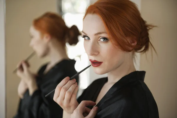 Retrato de una mujer pelirroja aplicando delineador de labios —  Fotos de Stock