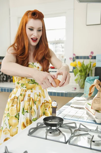 Young redheaded woman preparing omelet in kitchen — Stock Photo, Image