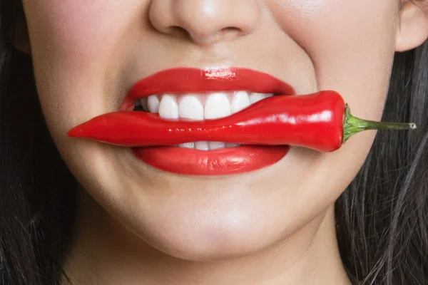 Close-up portrait of Hispanic woman biting red pepper — Stock Photo, Image