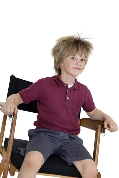 Niño de la escuela sentado en la silla del director sobre fondo blanco — Foto de Stock