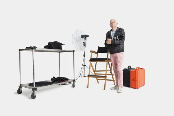 Porträtt av äldre man med kamera och utrustning står i fotografens studio — Stockfoto