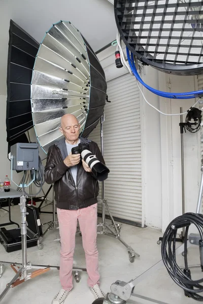 Senior photographer with camera in studio — Stock Photo, Image