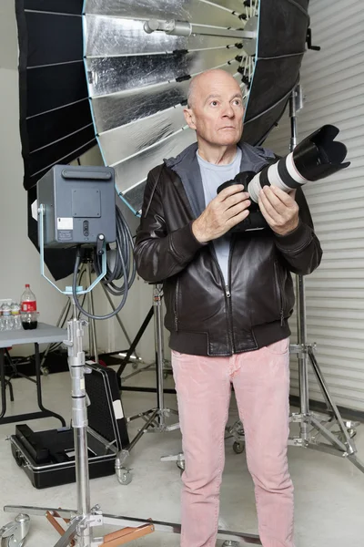 Vista frontal do homem sênior com câmera no estúdio do fotógrafo — Fotografia de Stock