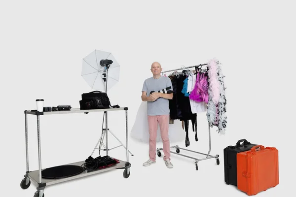 Retrato de fotógrafo sênior em pé na frente da prateleira de roupas em estúdio — Fotografia de Stock