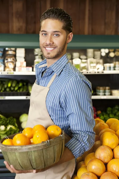 Buon venditore con cesto pieno di arance nel mercato — Foto Stock