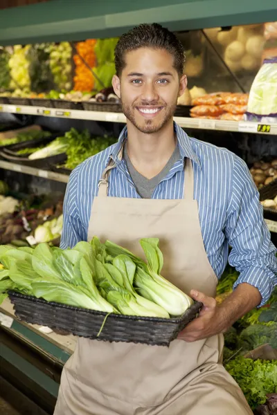 Portrait of a happy young salesperson with bok choy in market — Stock Photo, Image