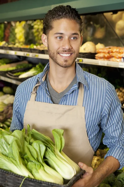 Feliz joven vendedor sosteniendo bok choy en el supermercado —  Fotos de Stock