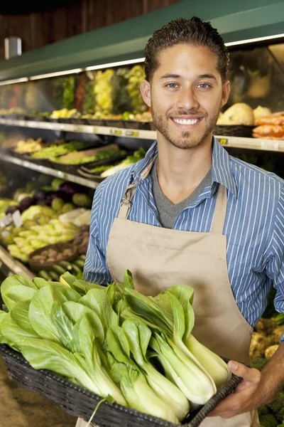 Portrait of handsome young sales clerk with bok choy in market — Stock Photo, Image