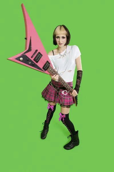 Mooie punk vrouw met gitaar op groene achtergrond — Stockfoto