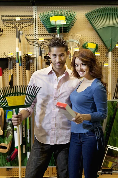 Retrato de pareja joven con garra de jardinería en tienda — Foto de Stock