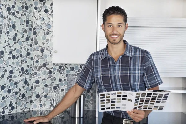 Portret van een jonge man met kleur monsters permanent in model huis keuken — Stockfoto
