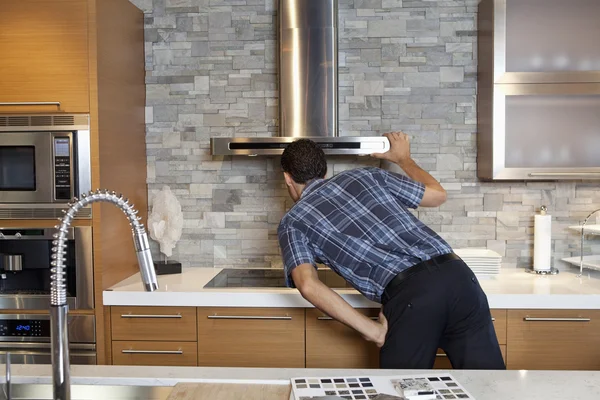 Visão traseira do jovem olhando para a chaminé em casa modelo cozinha — Fotografia de Stock