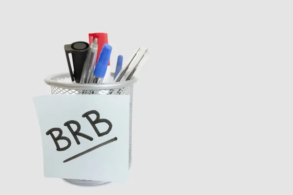 Close-up of sticky note with message on pen holder over white background — Stock Photo, Image