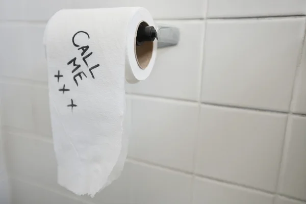 Close-up of toilet paper with text in bathroom — Stock Photo, Image