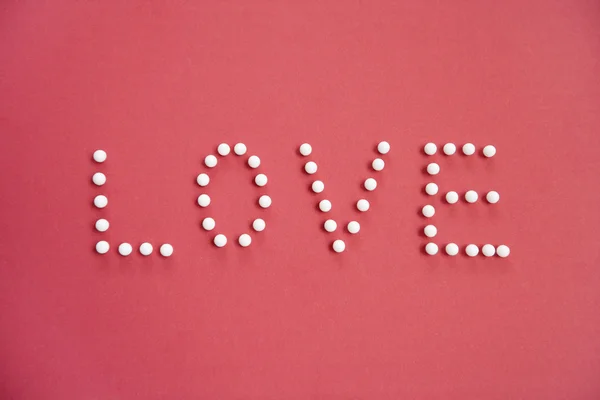 Close-up of push pins spelling love over colored background — Stock Photo, Image