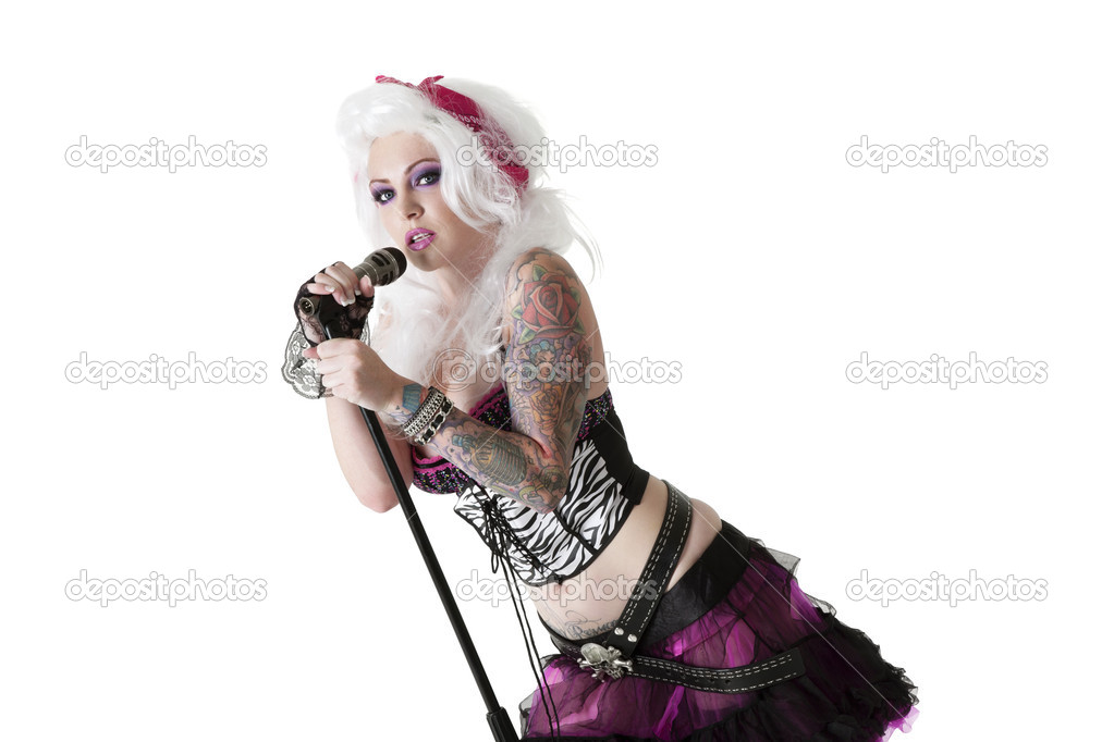 Portrait of beautiful young woman wearing wig while singing with microphone over white background