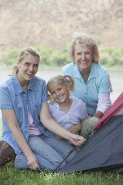 Woman With Mother And Daughter Putting Up A Tent clipart