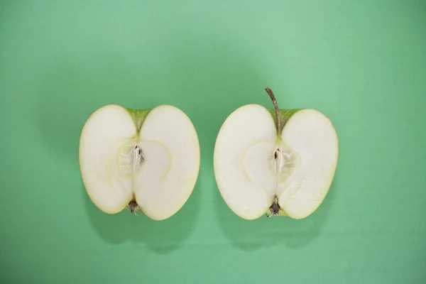 Нарезанное зеленое яблоко на зеленом фоне — стоковое фото