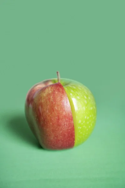 Red and green apple slices joined together over colored background — Stock Photo, Image
