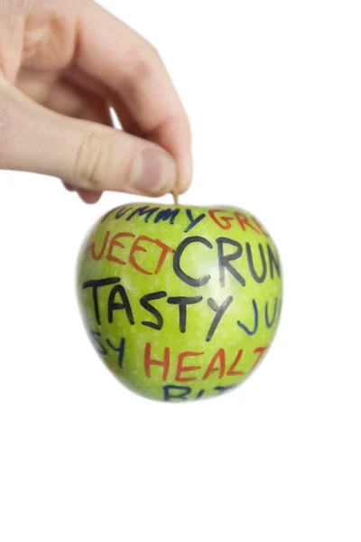 Image recadrée d'une main tenant une pomme granny smith avec du texte orthographique sur fond blanc — Photo