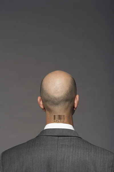 Bald headed businessman with barcode on his neck over gray background — Stock Photo, Image