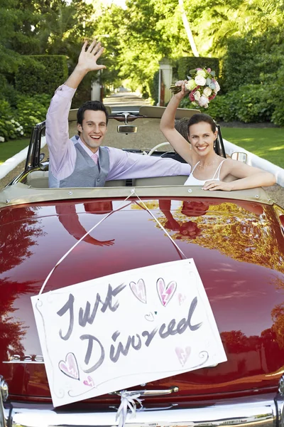 Pareja feliz en un auto convertible saludando con un cartel de divorcio — Foto de Stock