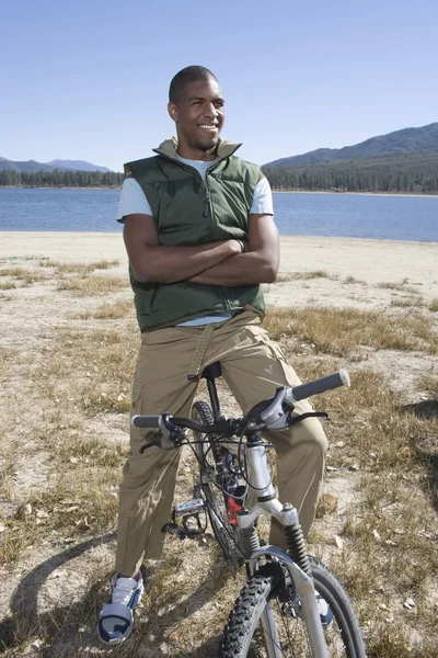 Homem sentado na bicicleta de montanha junto ao lago — Fotografia de Stock