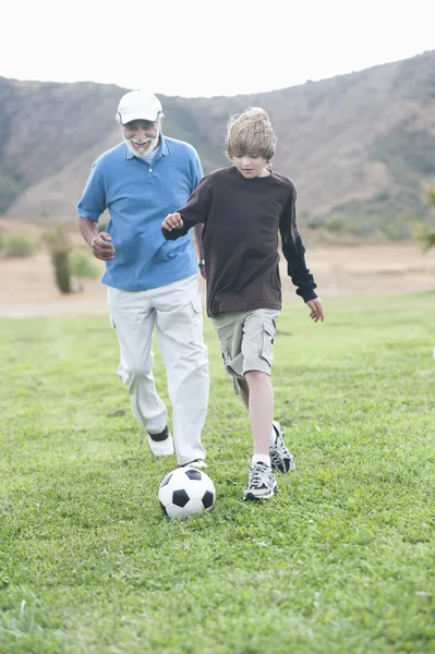 Dede ve torunu sahada futbol oynarken — Stok fotoğraf