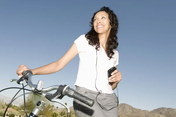 Mujer escucha MP3 sosteniendo manillar en bicicleta de montaña —  Fotos de Stock