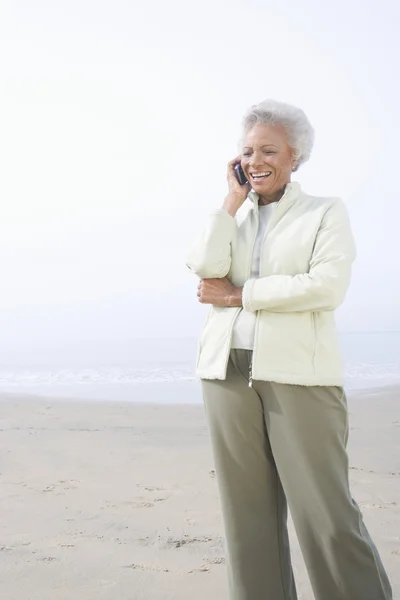 Starší žena na volání na pláži — Stock fotografie