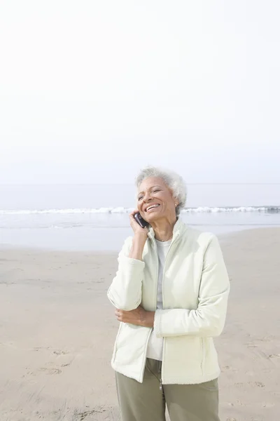 Äldre kvinna på samtal på stranden — Stockfoto