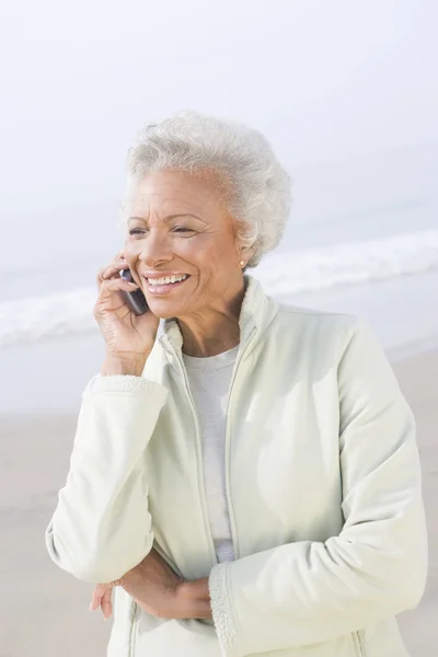 Äldre kvinna på samtal på stranden — Stockfoto